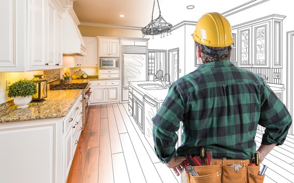 Male Contractor with Hard Hat and Tool Belt Looking At Custom Ki